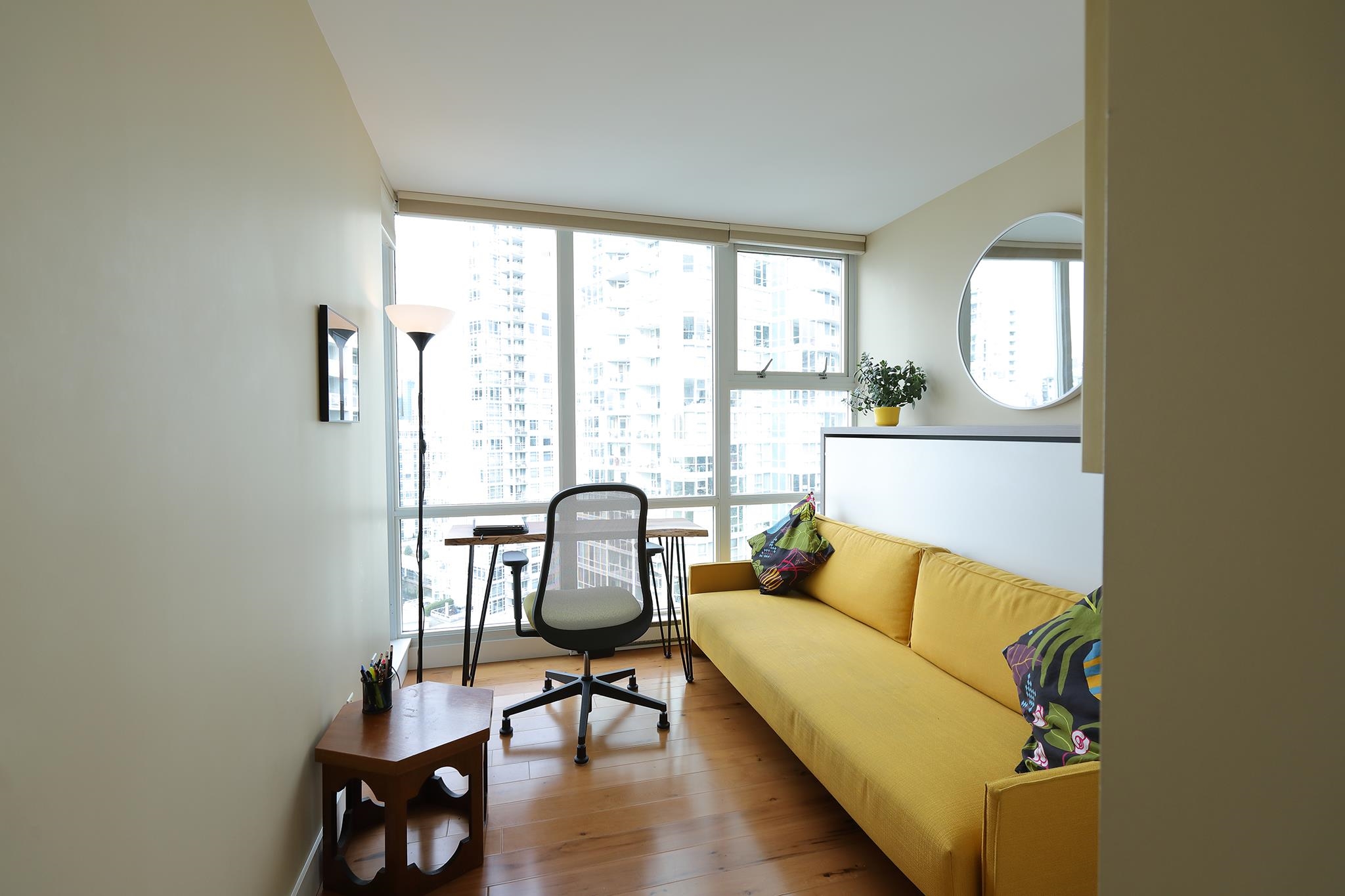 The small room off the hall set up as a study, a desk under the corner windows and a sofa along the wall.