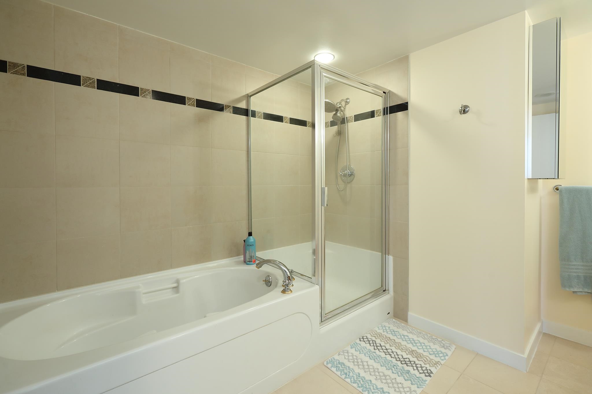 The ensuite, a soaker tub along the tiled wall with a separate glass shower beside it.