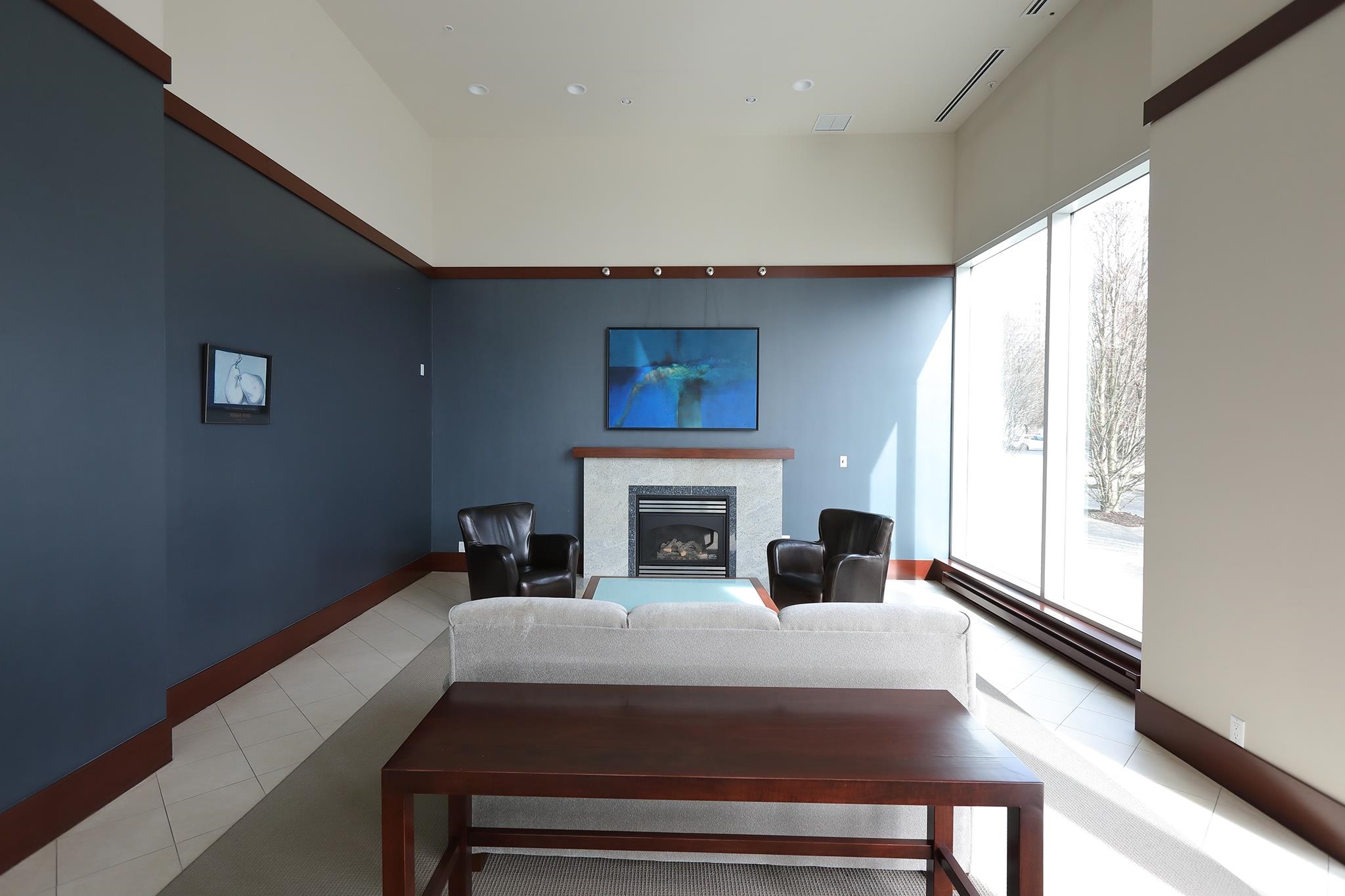 The building's lobby lounge, leather chairs drawn up to a stone fireplace under a tall window.