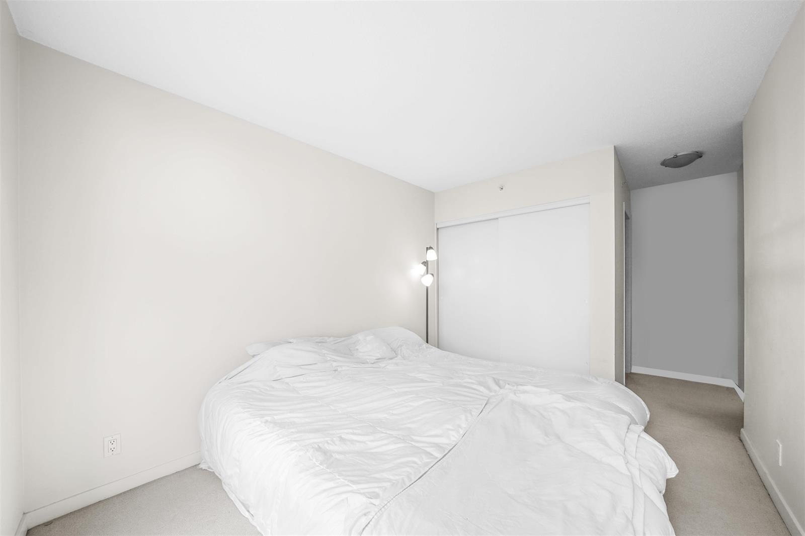 The second bedroom, empty, the closet doors along one wall.