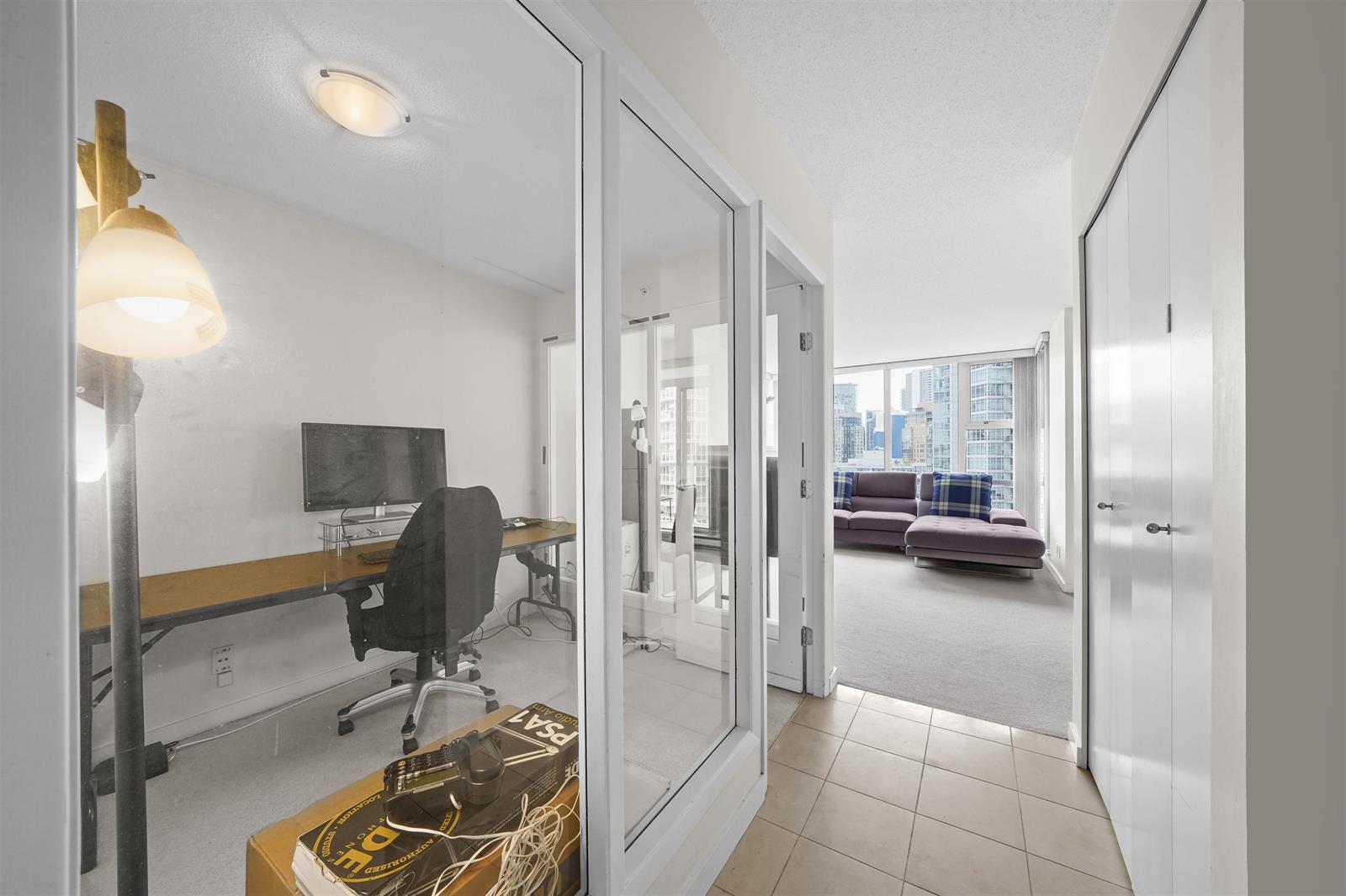 The den from the hall, mirrored closet doors carrying the window back into the room.