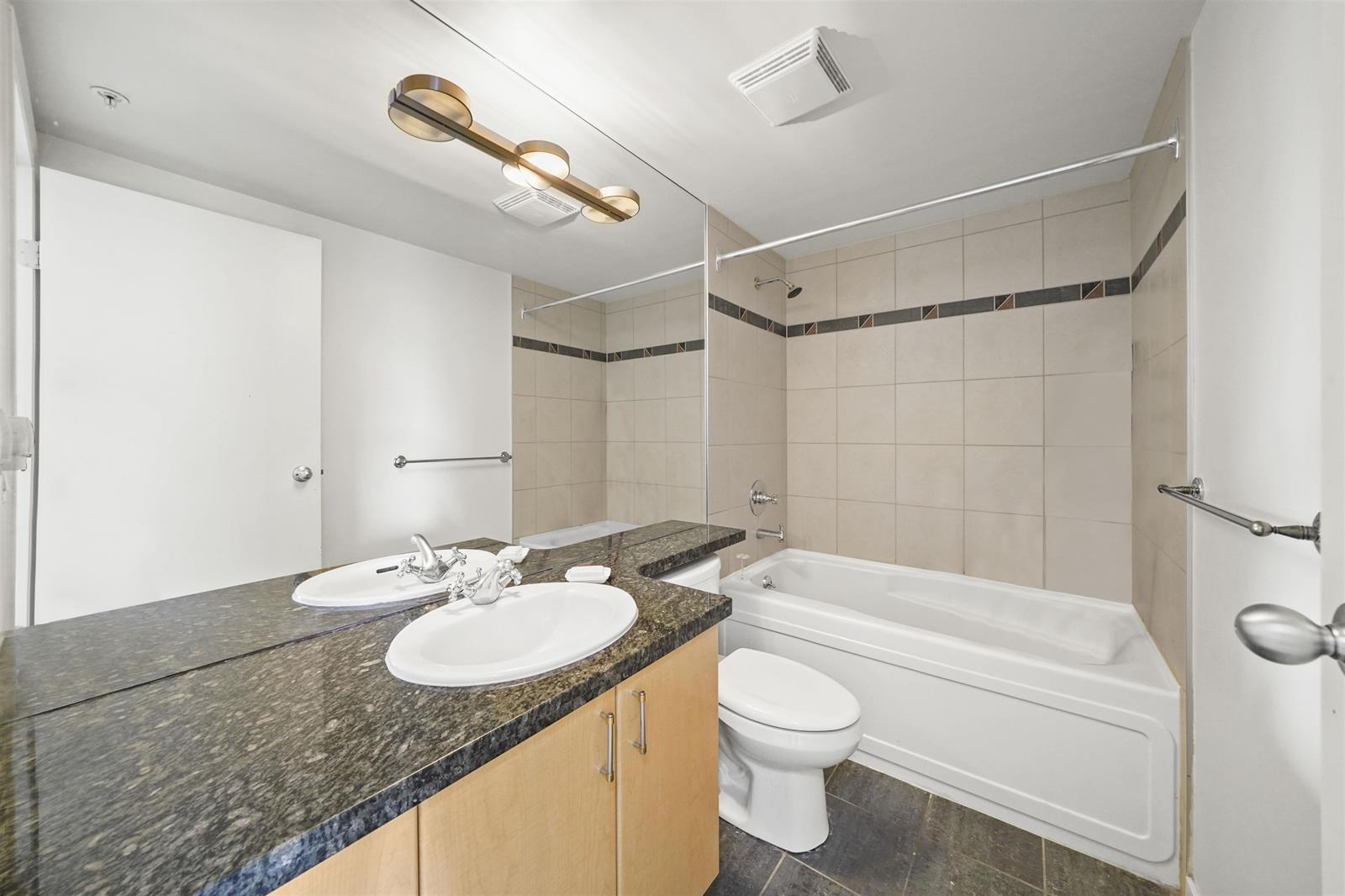 The bathroom from the door, the granite counter running to the tub under its tiled surround.