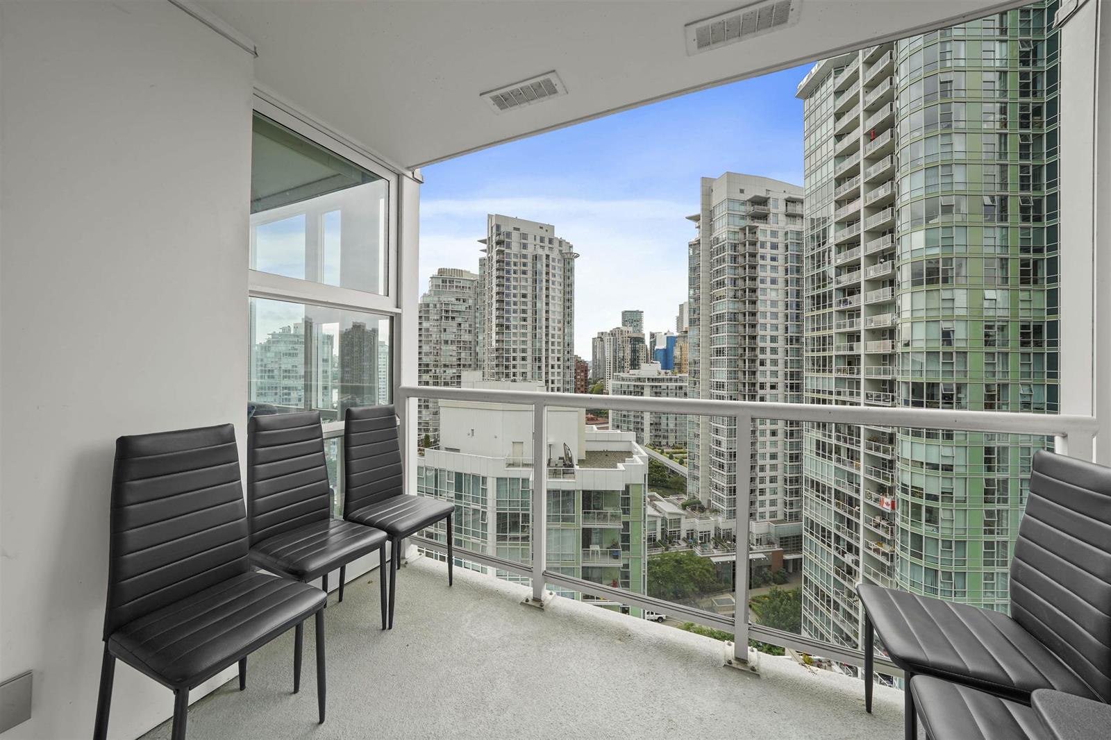 The covered balcony, chairs along the rail, looking across to the towers and down onto the green.