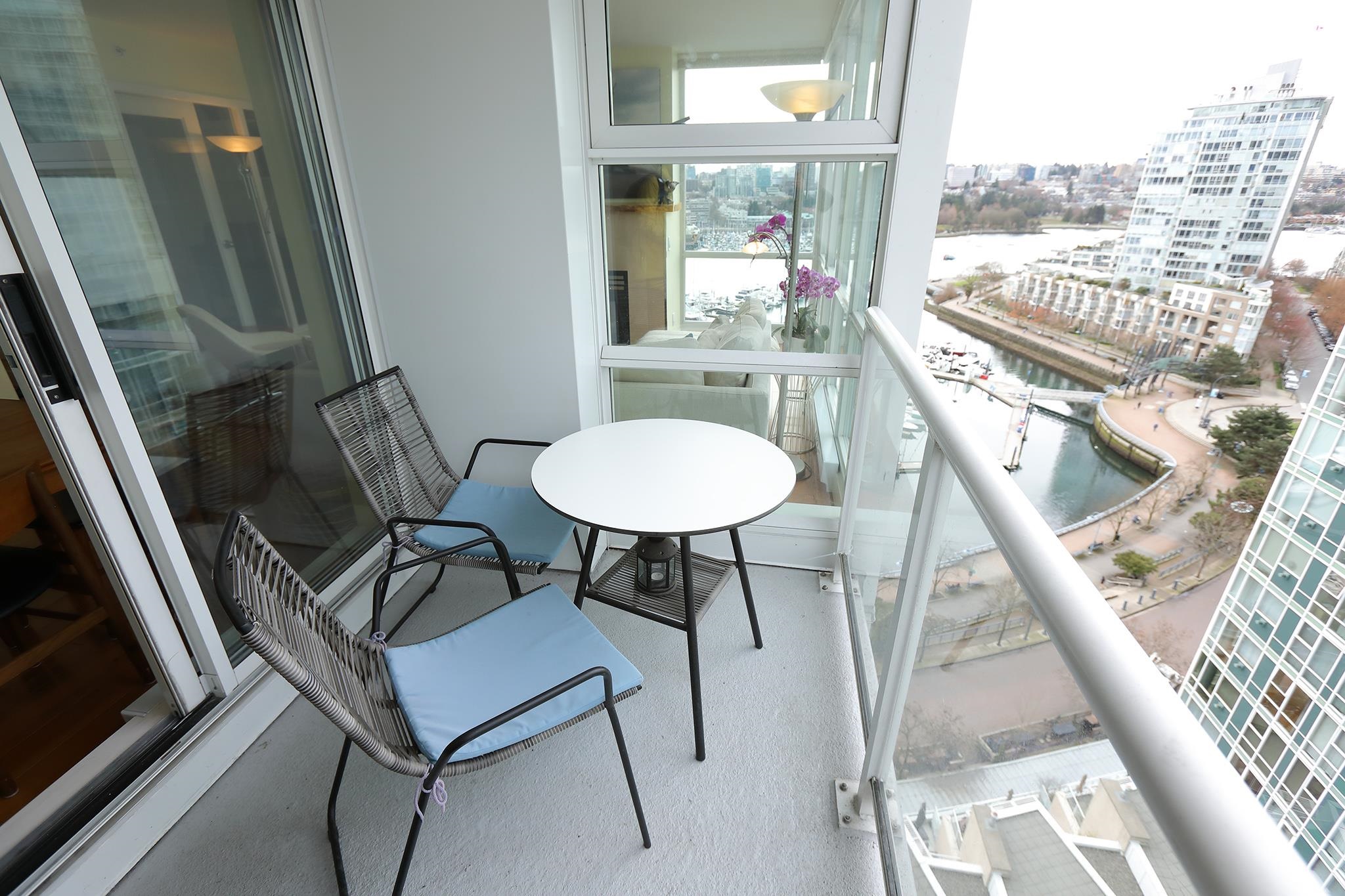 The balcony, two chairs and a small round table, looking straight down onto the marina and the seawall.