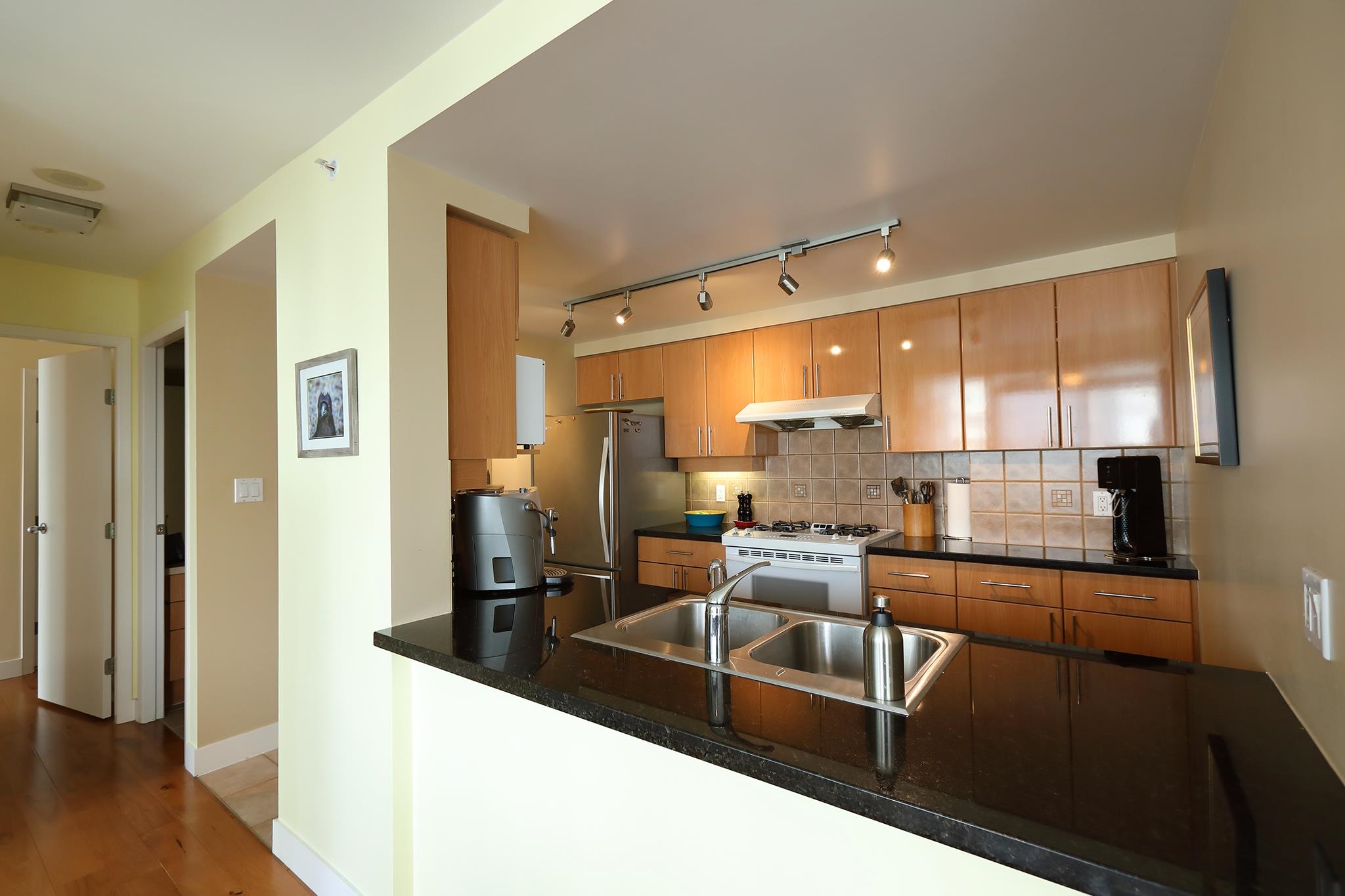 The kitchen from the pass-through, the fridge and range at the far end and the hall doors to one side.