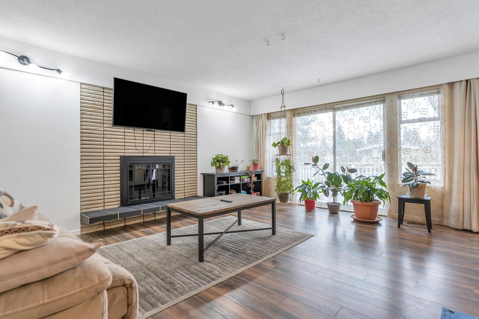 The living room, a brick-faced fireplace on one wall and a run of windows to the garden.
