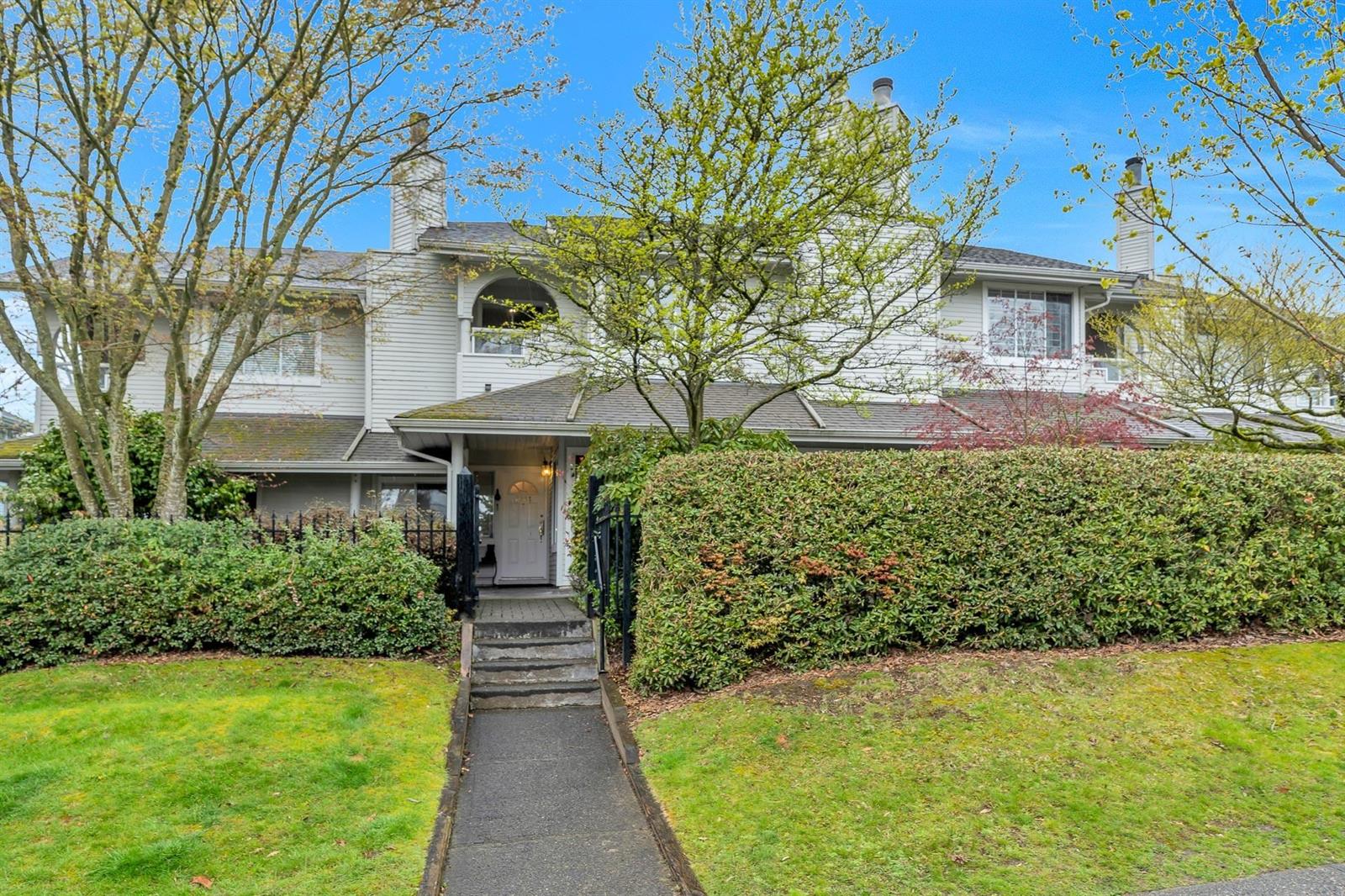 The house from the front path, two storeys behind a clipped hedge and a small lawn.