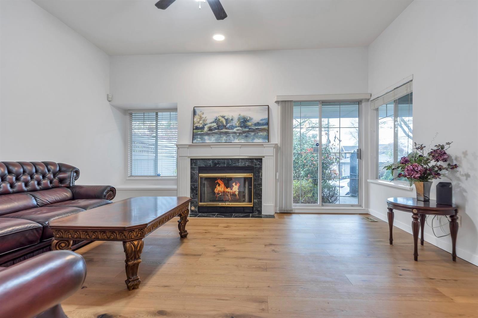 The living room from the far end, looking back past the fireplace to the windows and the garden beyond.
