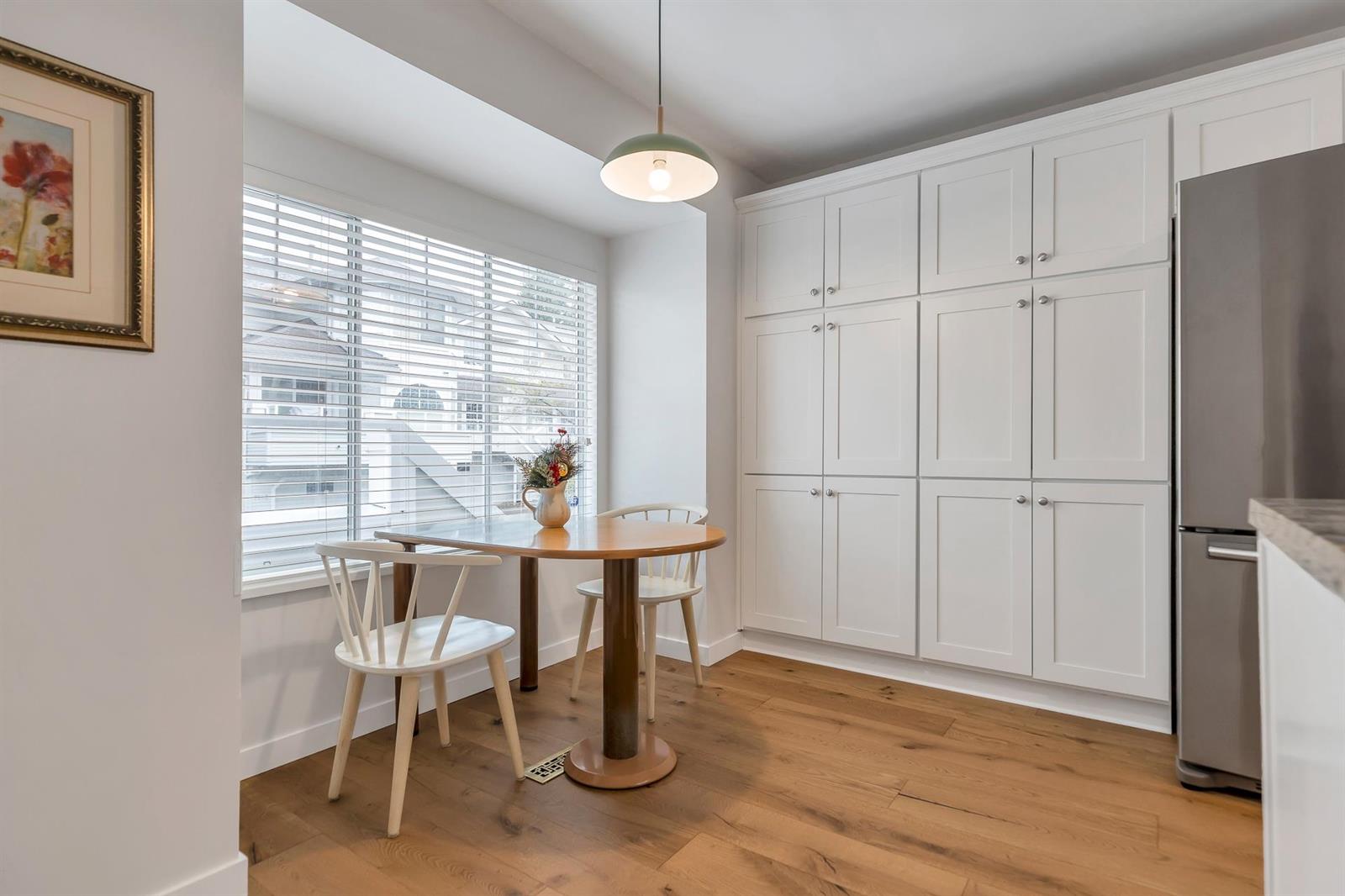The eating nook, a small round table at the window with cupboards to the ceiling beside it.