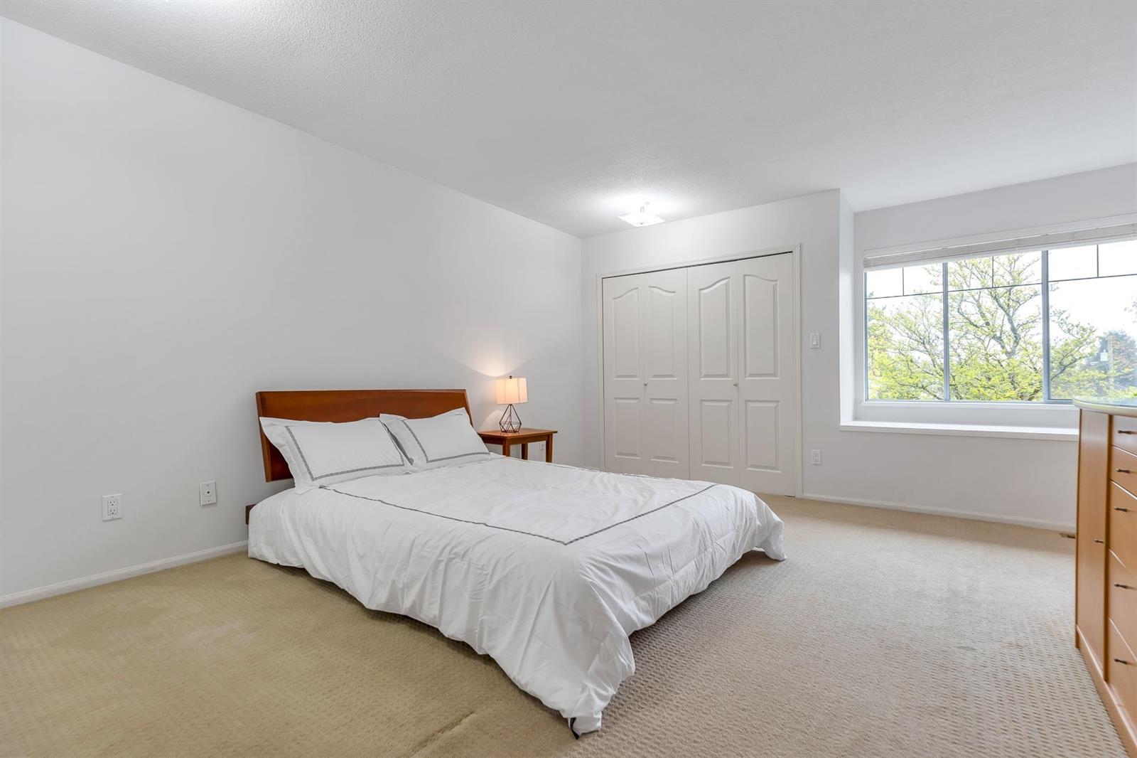 A bedroom, with a window over the garden and closets along the far wall.