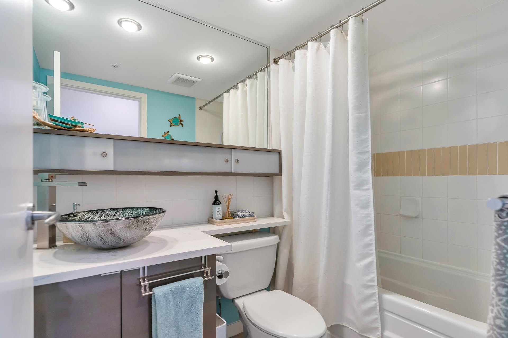 The other bathroom, a tub along the wall beside a vessel sink.
