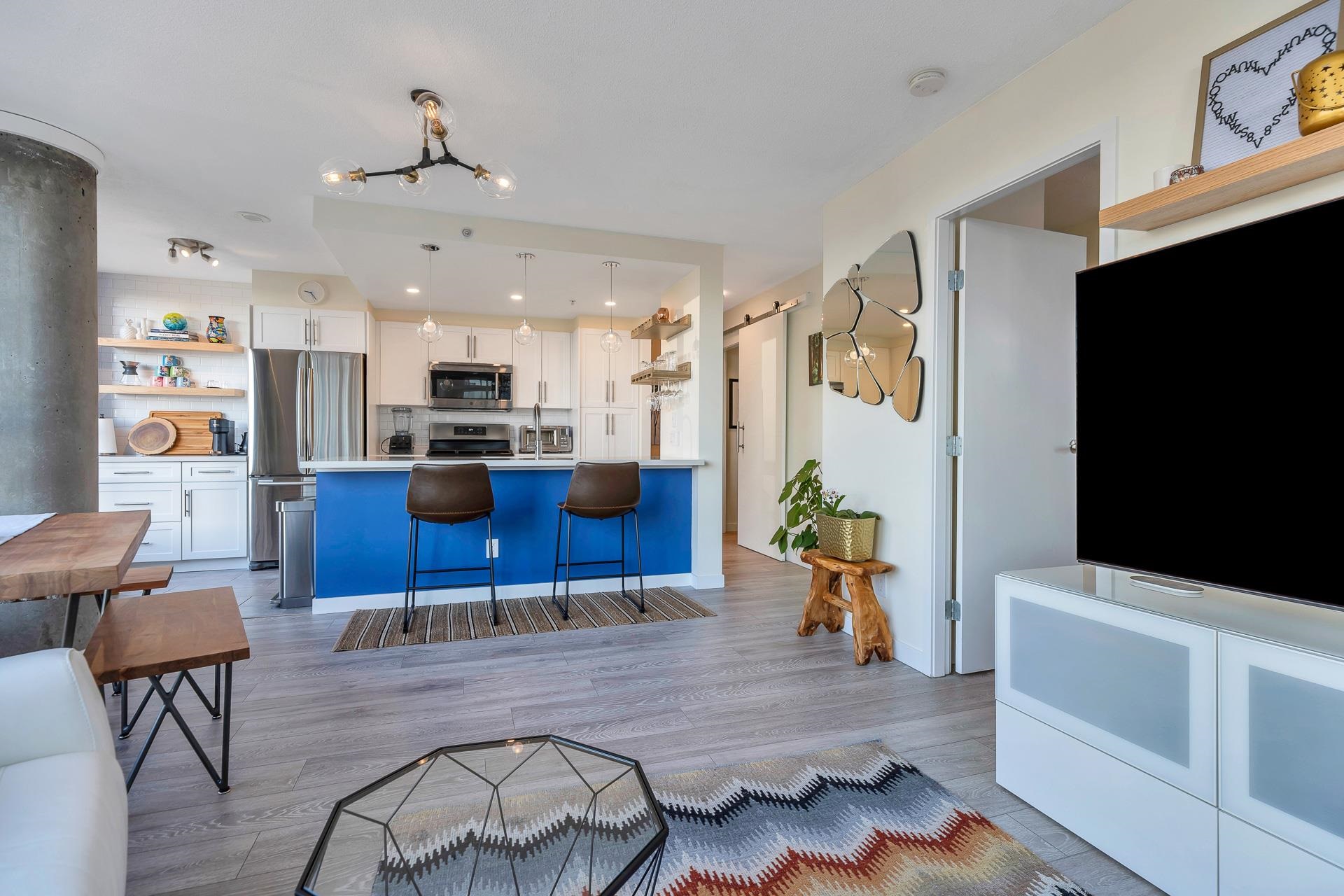 The living room towards the entry, the kitchen island beyond it and a barn door to the hall.