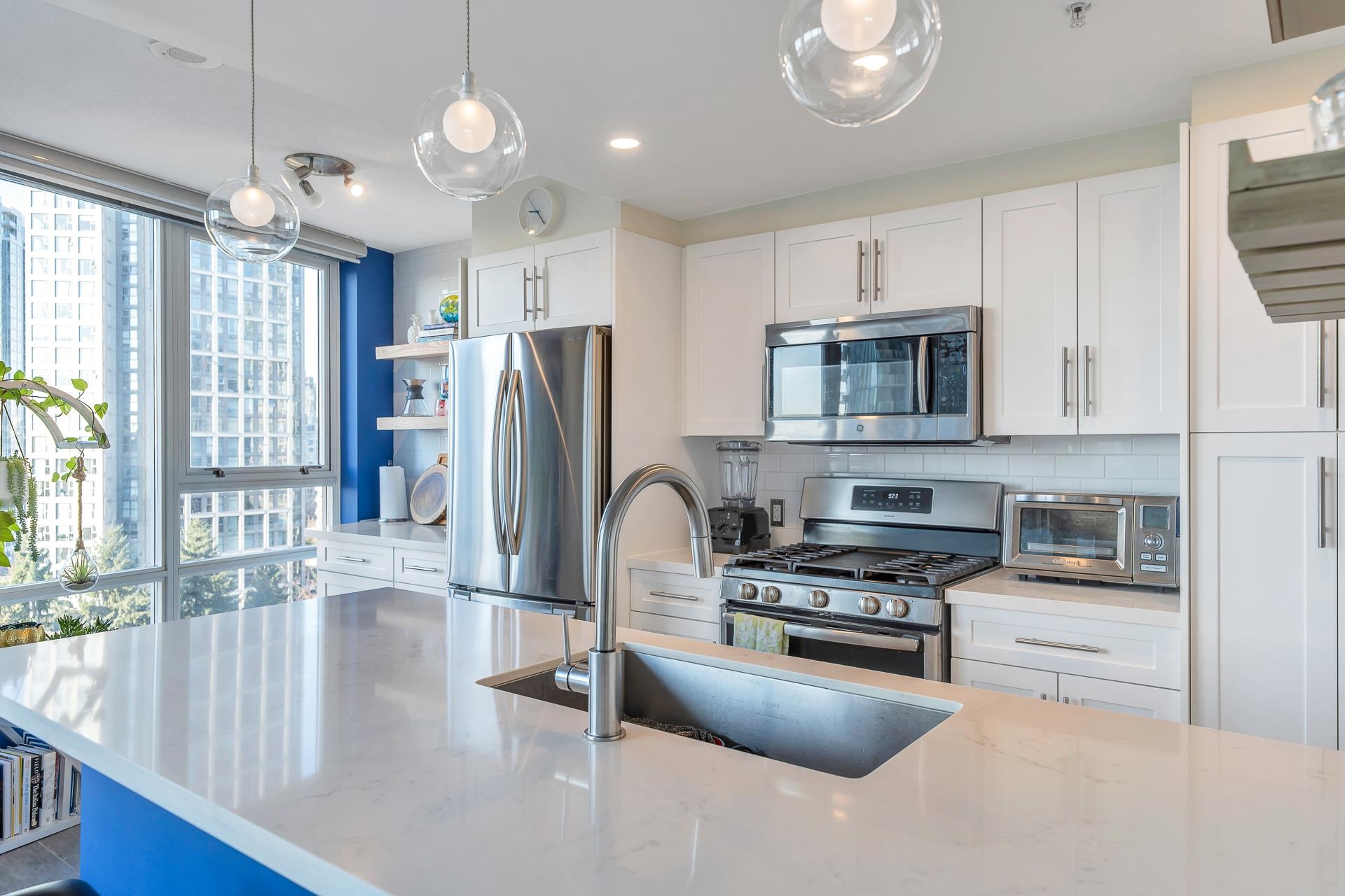 The kitchen island, a quartz top over a blue base, with the range and fridge along the wall behind.