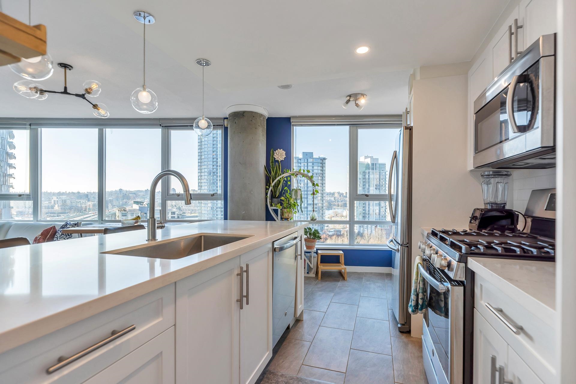 The island sink under a tall tap, the gas range past it and the city filling the windows.