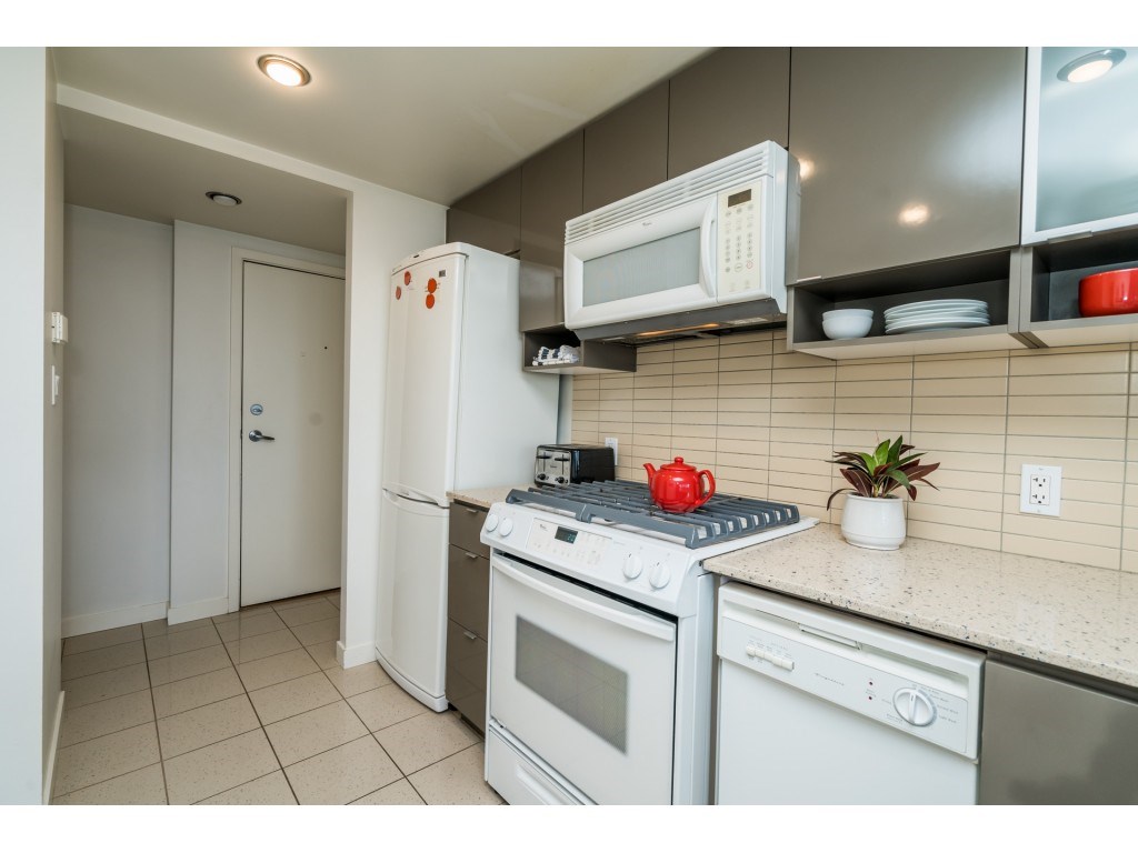 The range and dishwasher in white against grey cabinets, wall cupboards above.