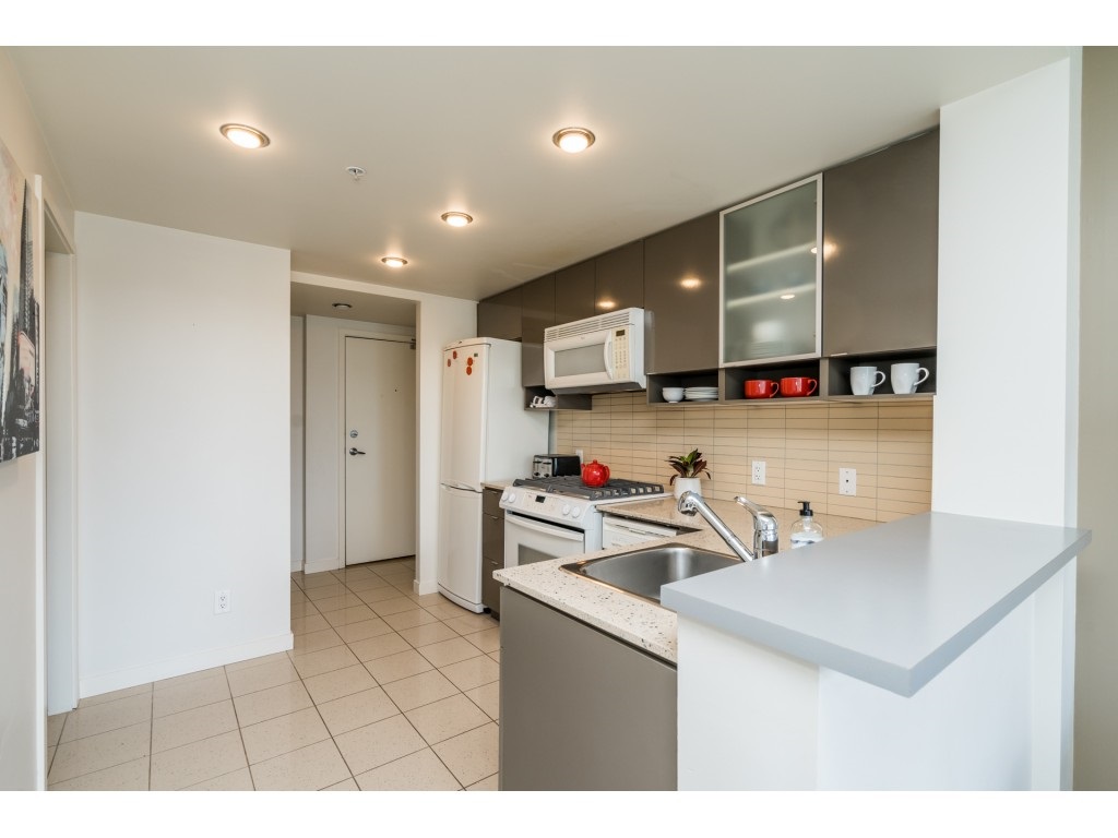 The kitchen from the living area, a pale counter turning the corner and tile underfoot.