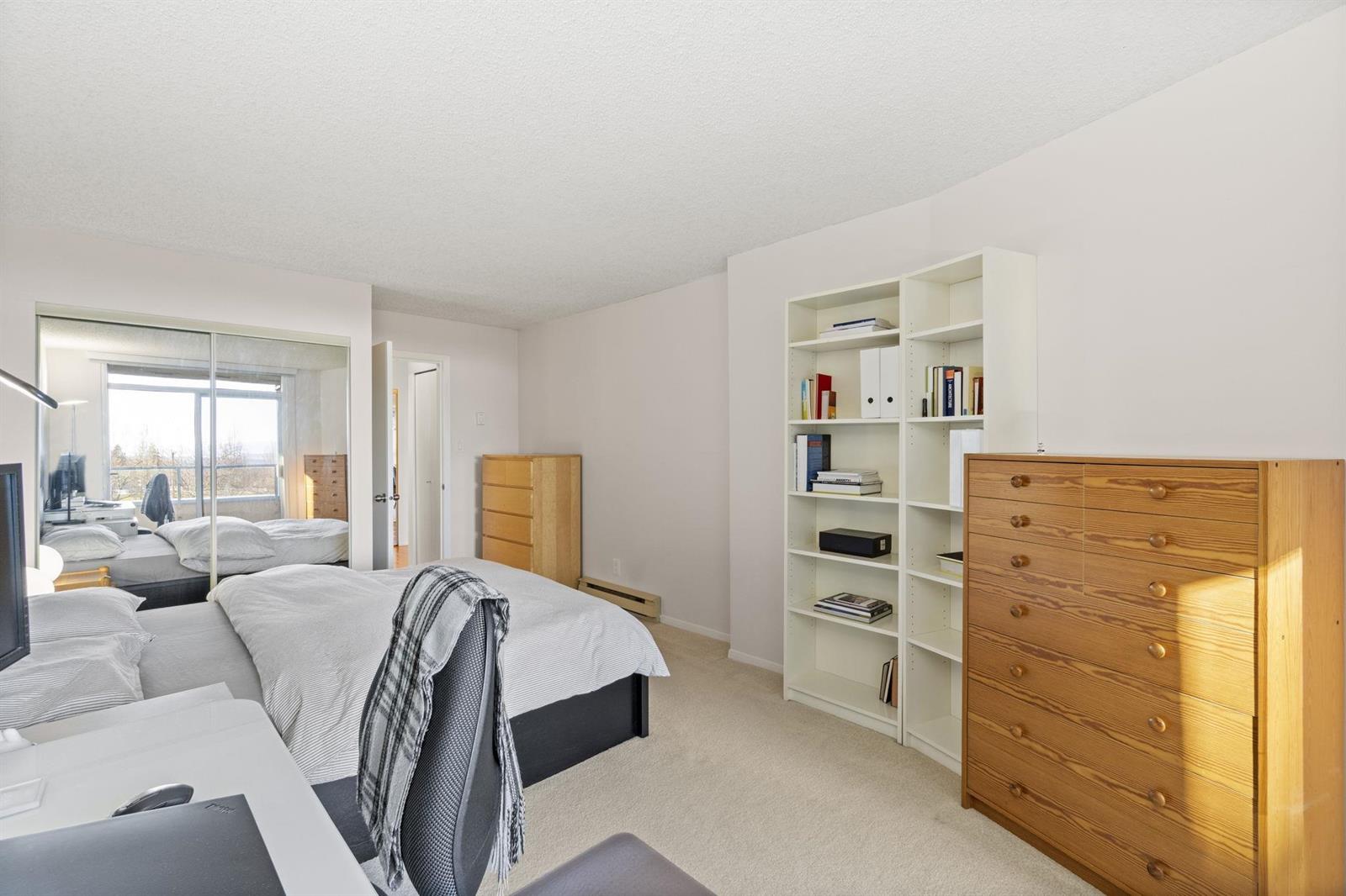 The bedroom from the other side, a chest of drawers and a bookcase along the far wall.