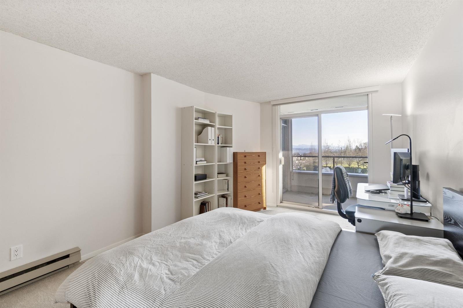 The bedroom looking toward the window, shelving on the left and the balcony beyond.