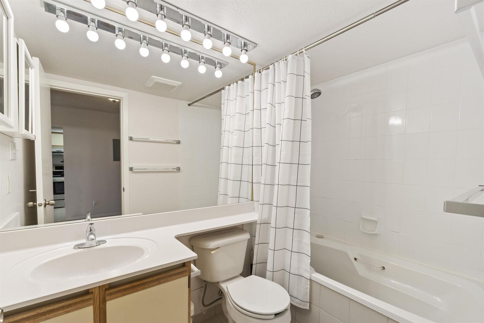 The bathroom, a vanity and mirror beside the tub and shower.