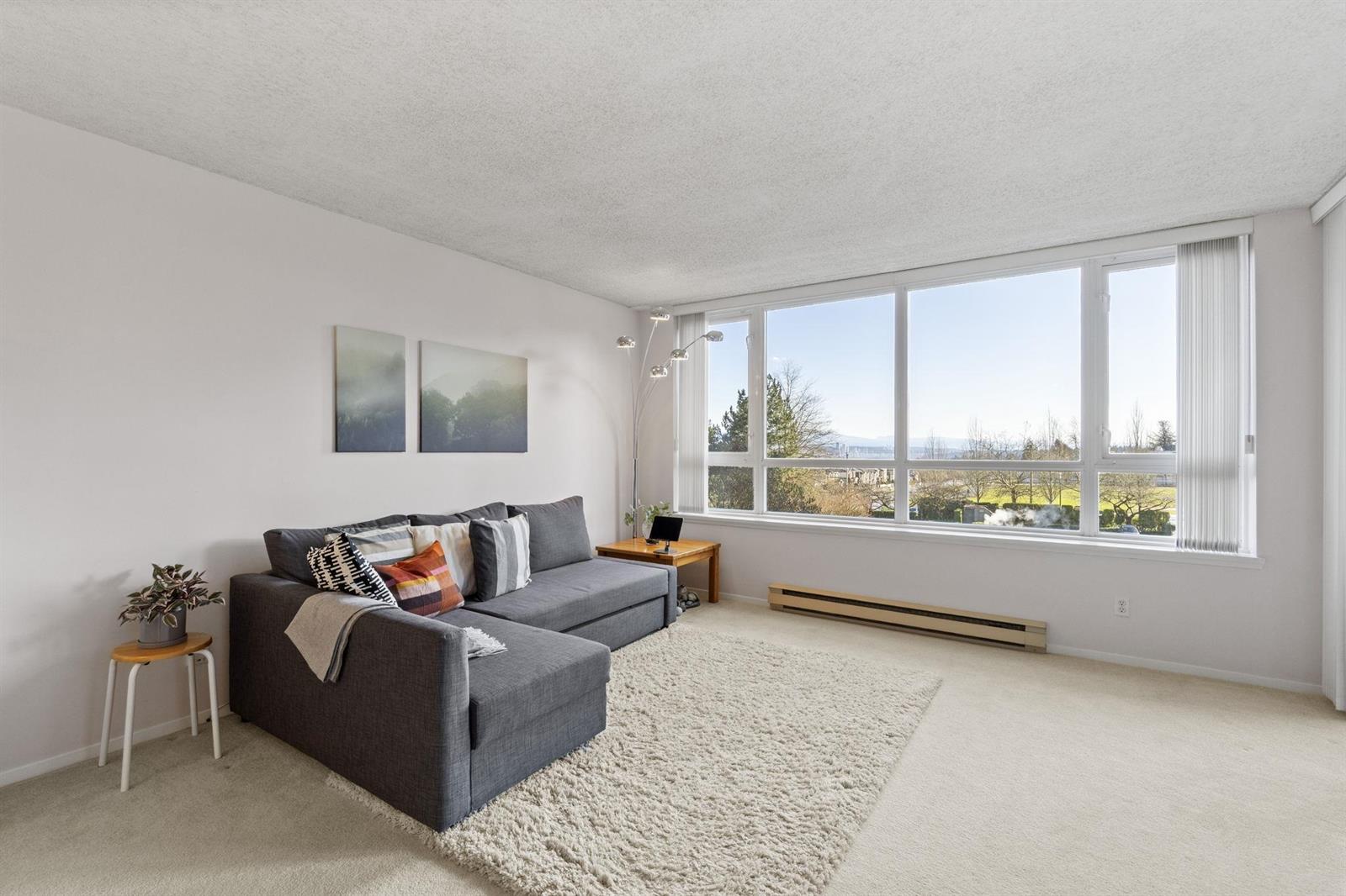 The living room, a sofa on a pale rug with windows running the length of the outside wall.