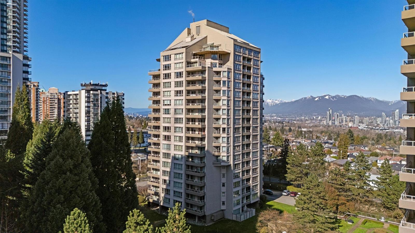 The outlook from the building over the treetops toward Metrotown and the mountains.