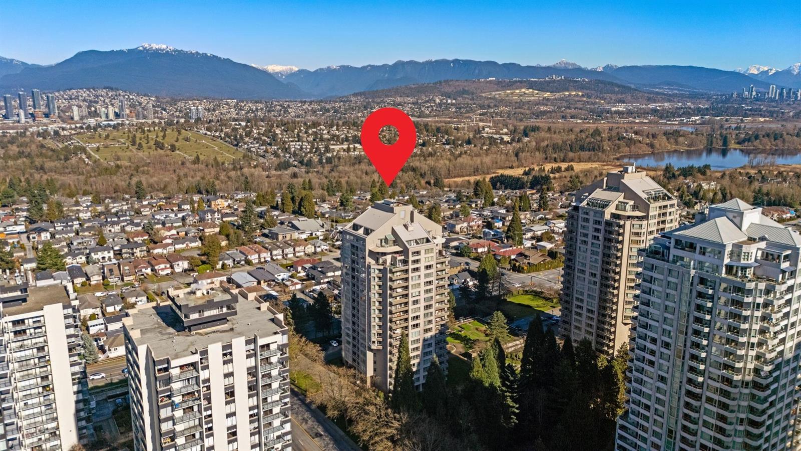 An aerial view of the grounds, the two towers among the trees with the mountains behind.
