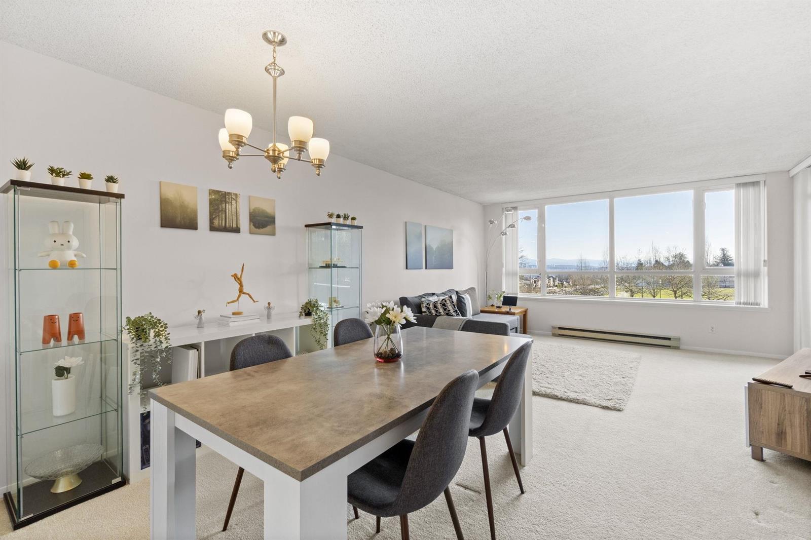 The dining room, a table for six beneath a chandelier with a glass cabinet against the wall.
