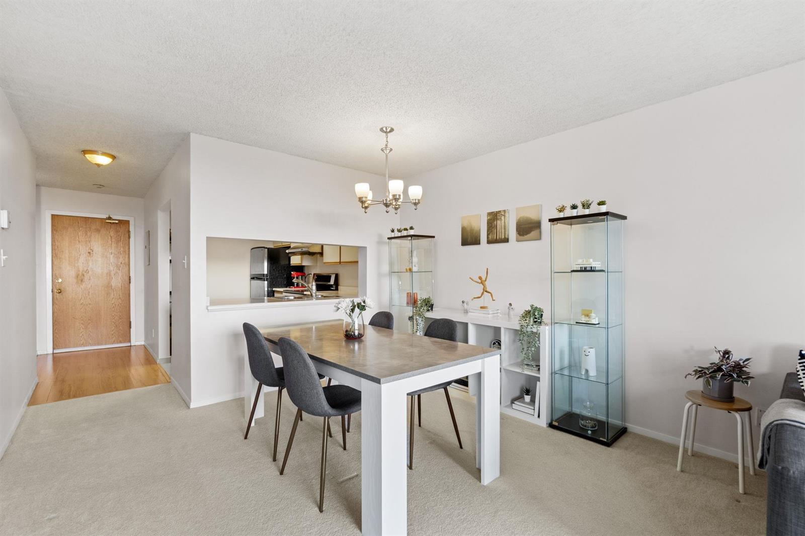 The dining area from the living room, the entry door and the kitchen window beyond.