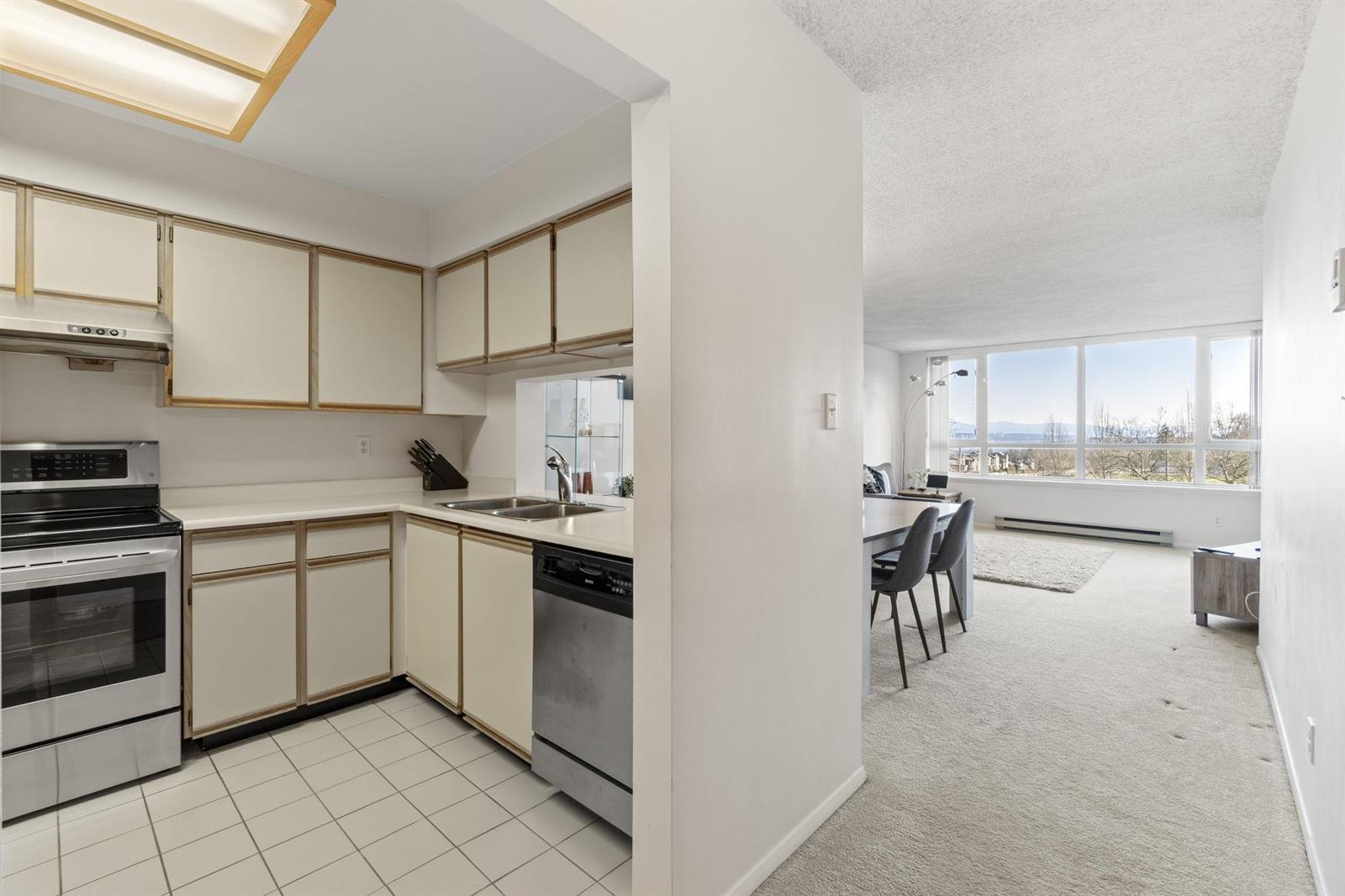 The kitchen, an L of cabinetry with the range on the left and the dining room through the opening.