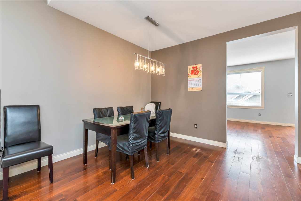 The dining room, a dark table under a linear pendant against a grey wall.
