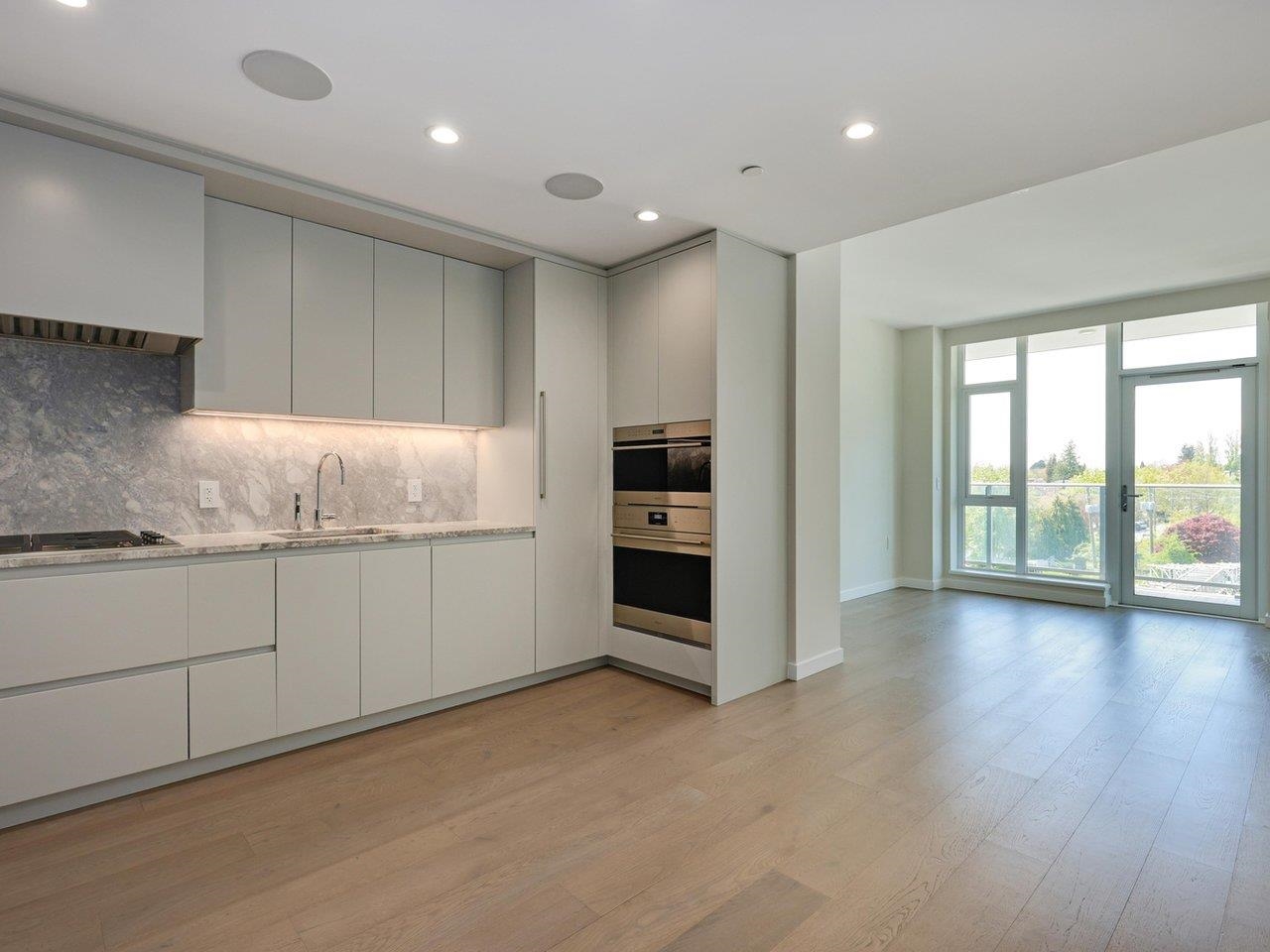The kitchen along the left wall, with the living area and its balcony doors beyond.