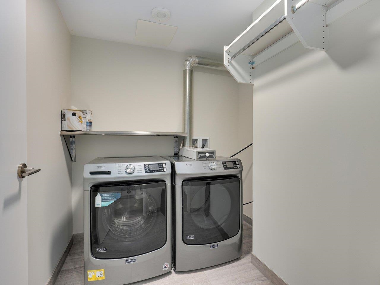 The laundry room, with a full-size washer and dryer side by side and the air handling unit above.