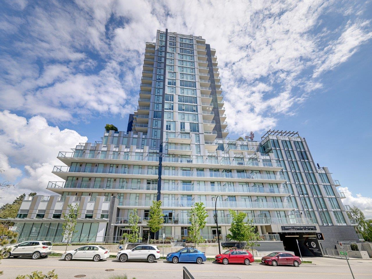 The building from the street: a pale glass and concrete tower stepping down to townhouses at its foot.