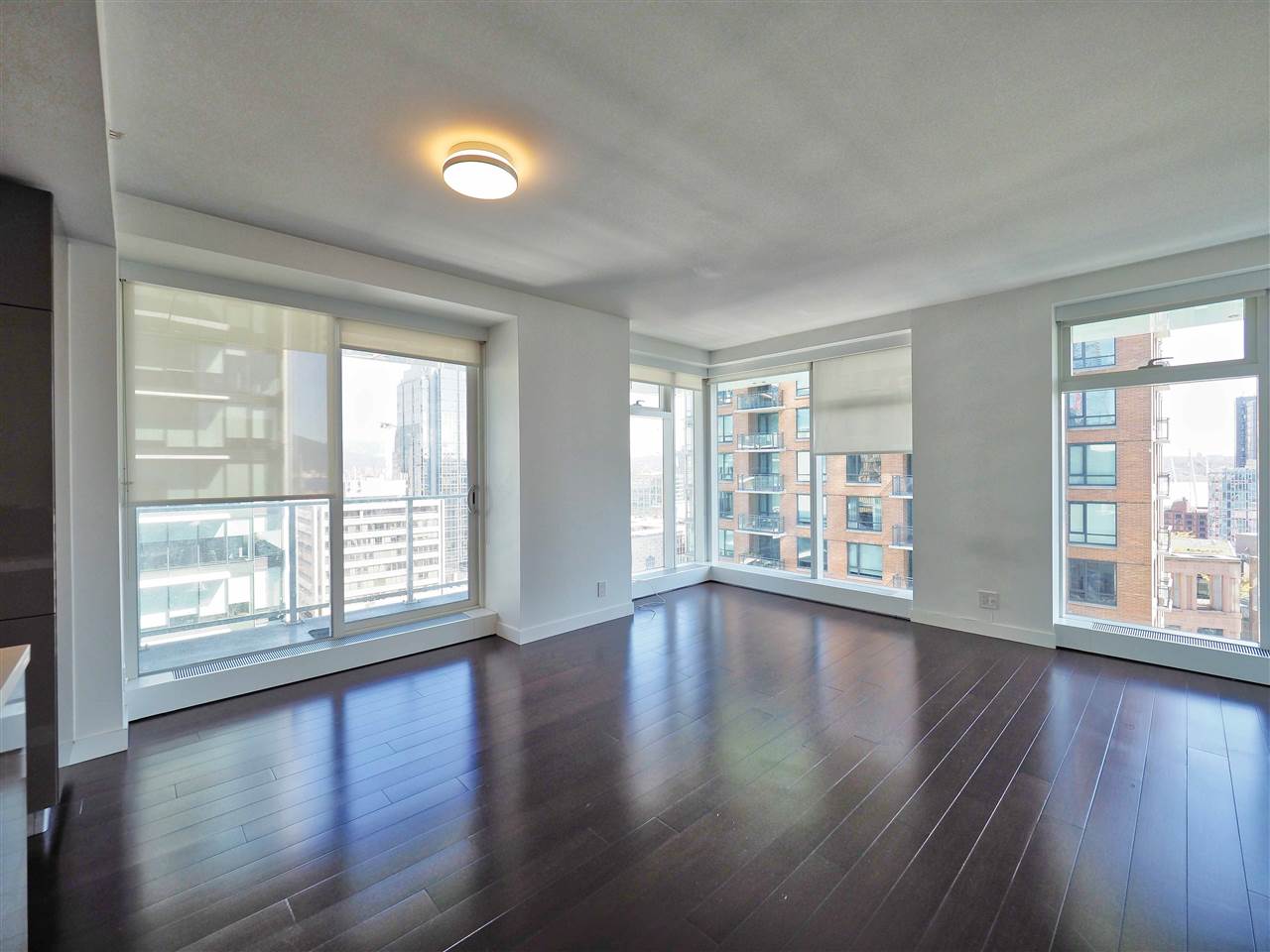 The corner of the living room, two window walls meeting and the city stepping away beyond the glass.