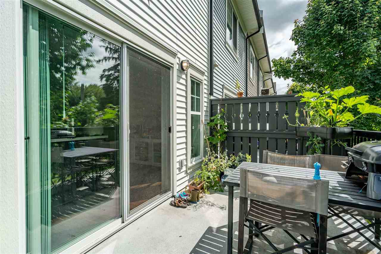The deck looking back at the home, sliding glass doors in the siding with the trees crowding in at the side.