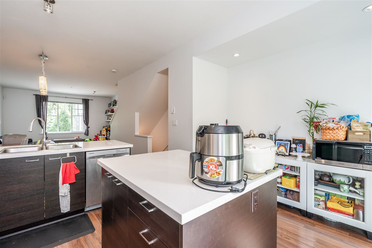 The kitchen counter, appliances along the quartz with the window over the sink.