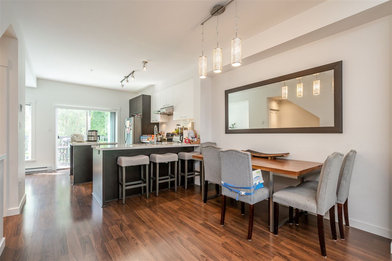 The dining room, a table under a wide framed mirror with the kitchen island behind.