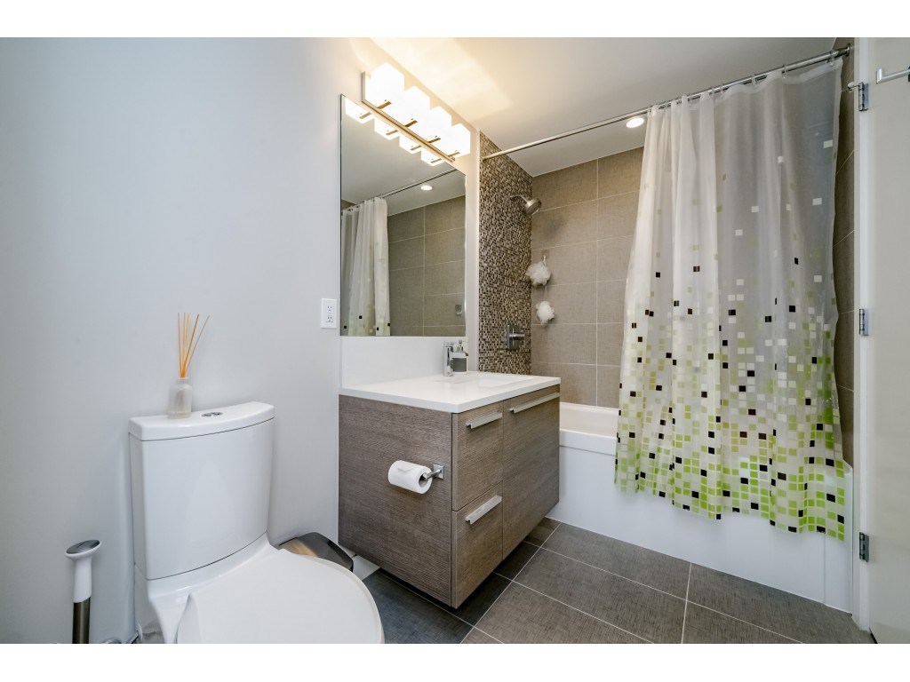 The bathroom, a floating vanity under a lit mirror with the shower behind the curtain.
