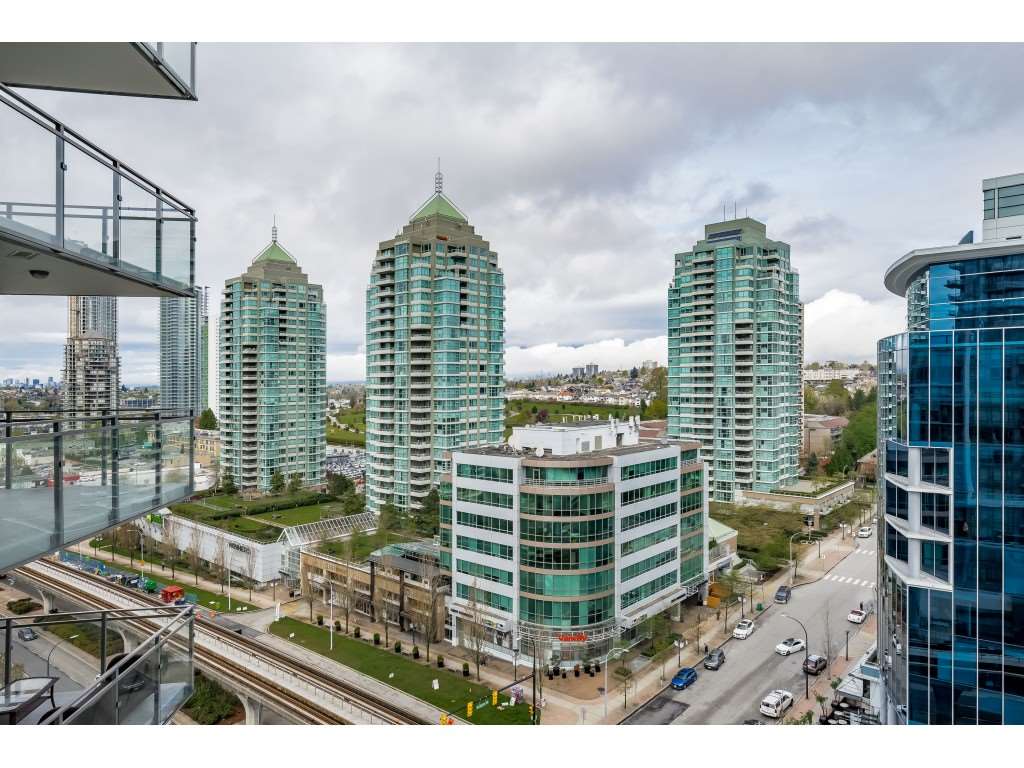 Looking down from the balcony onto the green glass of the neighbouring towers and the street.