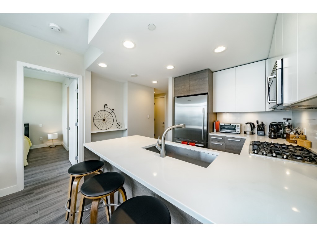 The kitchen from the island, gas range and stainless appliances with the bedroom door beyond.