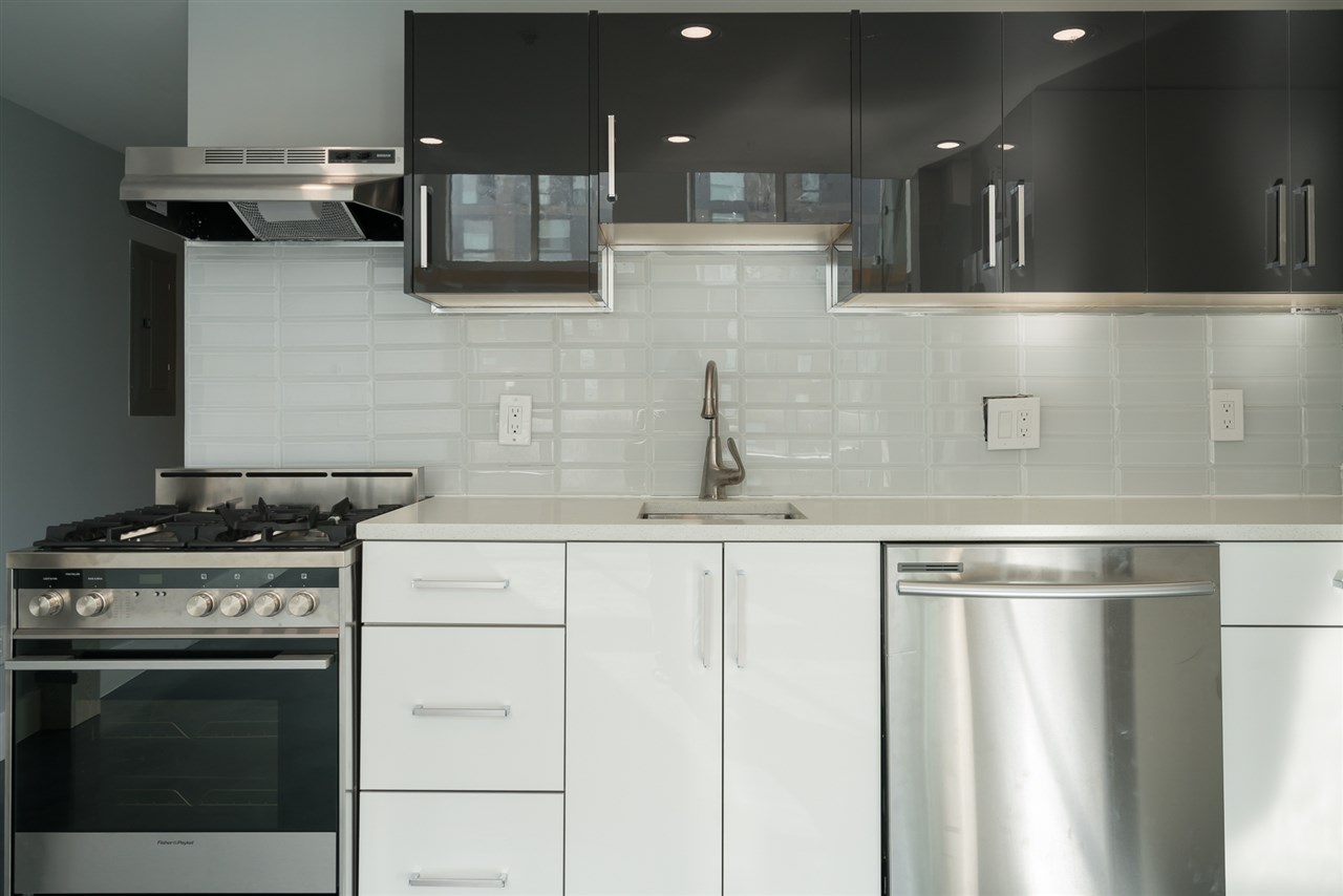 The kitchen counter closer in, white tiled backsplash above the range and the sink.