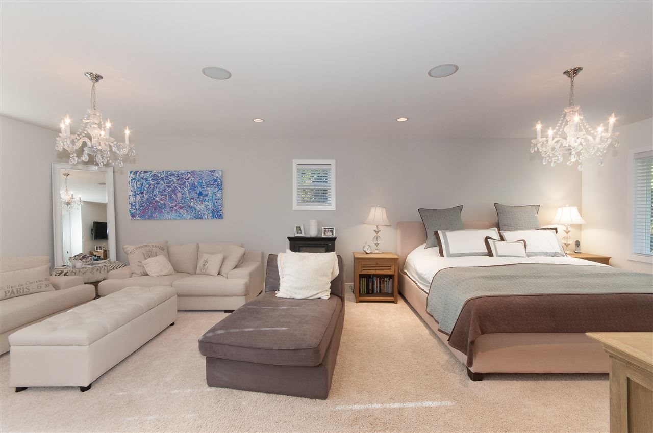 The primary bedroom, a chandelier above the bed and a sitting area at the foot.