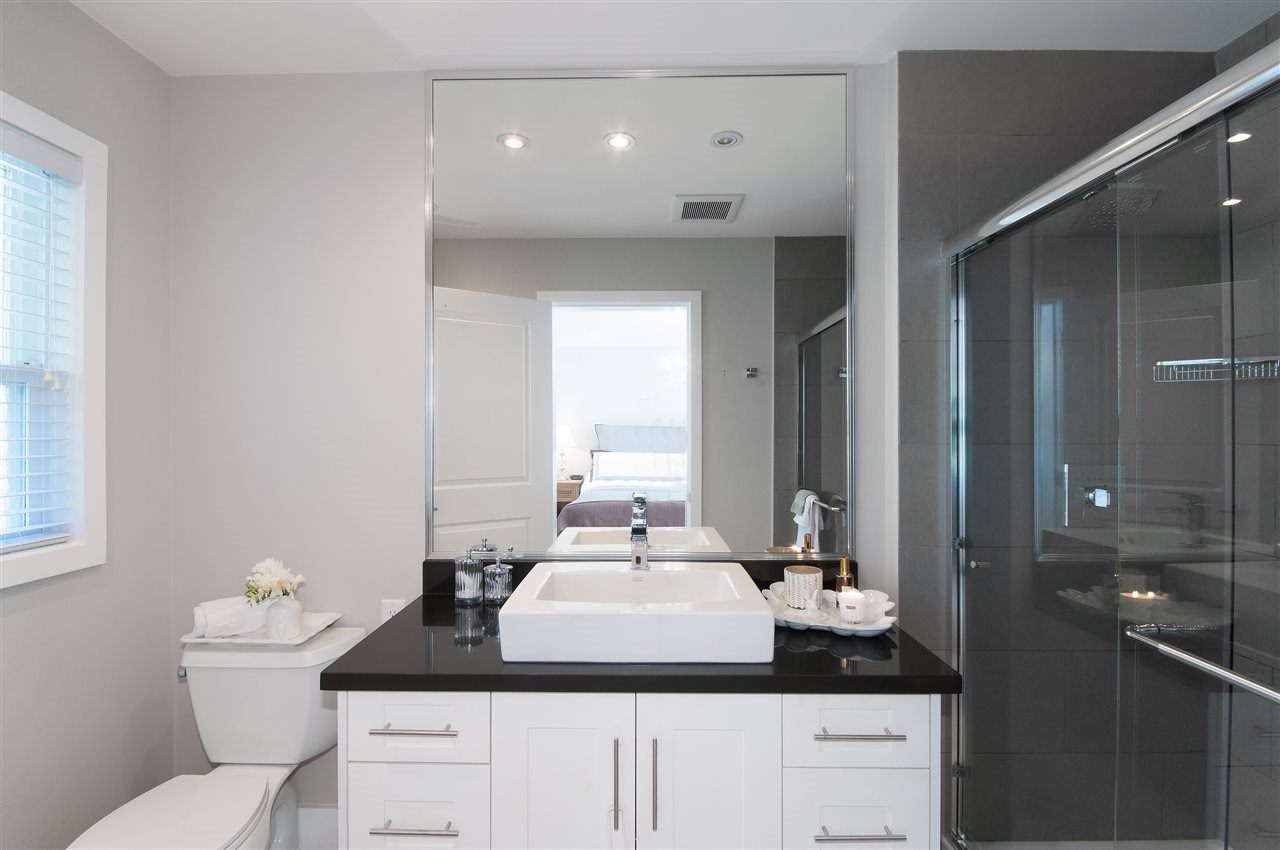 The ensuite, a double vanity on dark stone beside a glass shower.