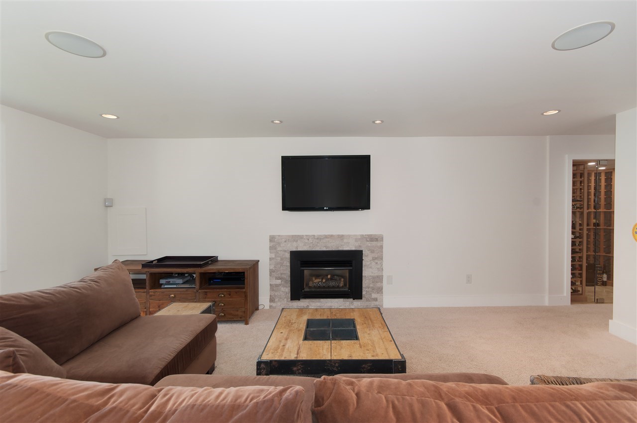The recreation room downstairs, a sectional facing a fireplace and a television.