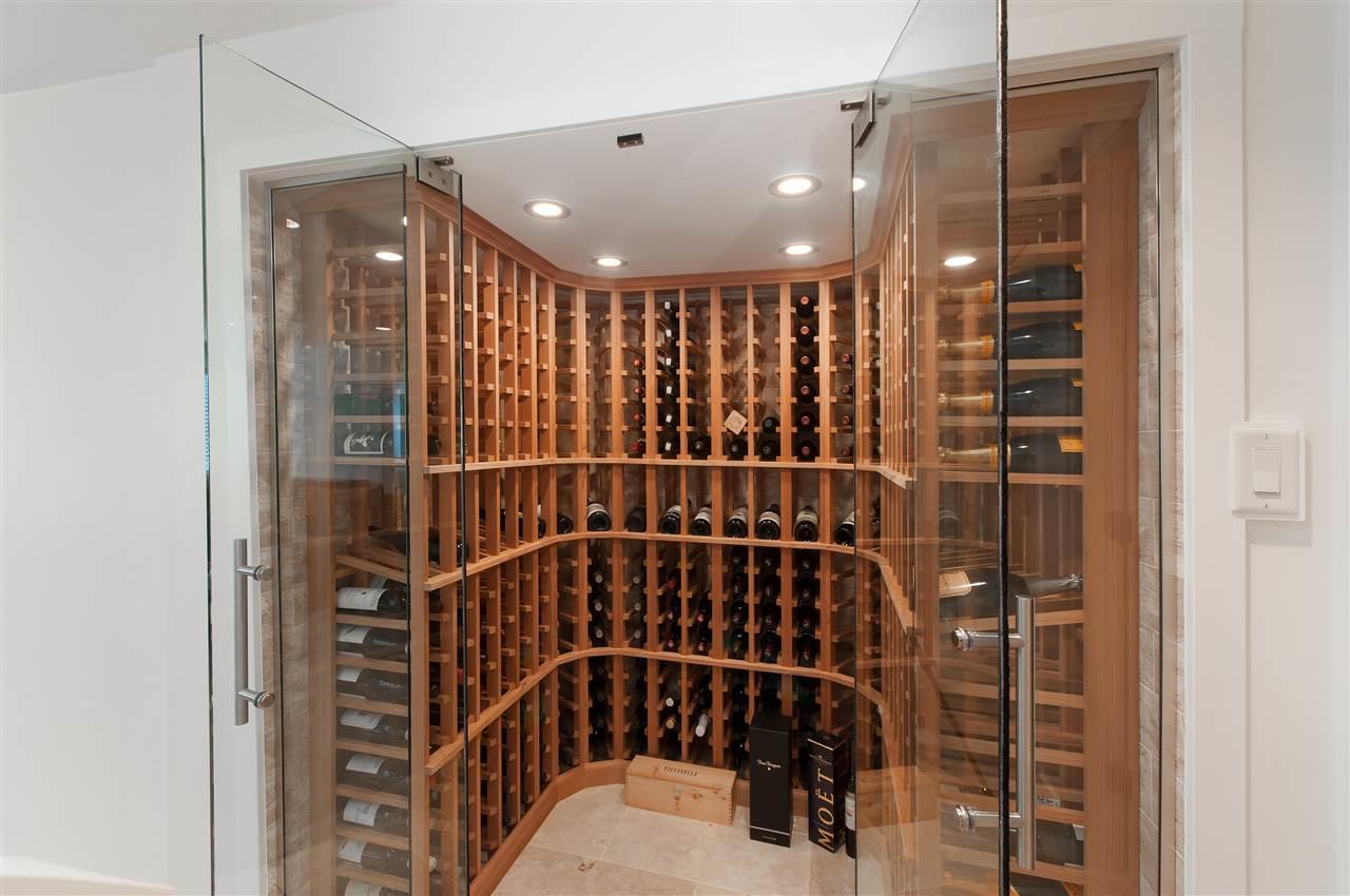 The wine room, racks of bottles behind a glass wall.