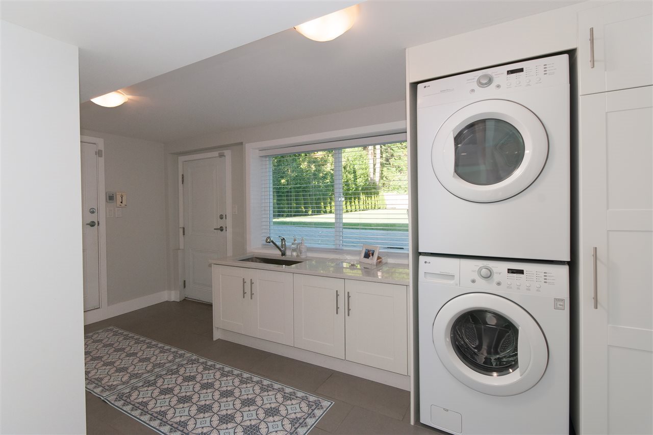The laundry room, a stacked washer and dryer beside a run of white cabinets.
