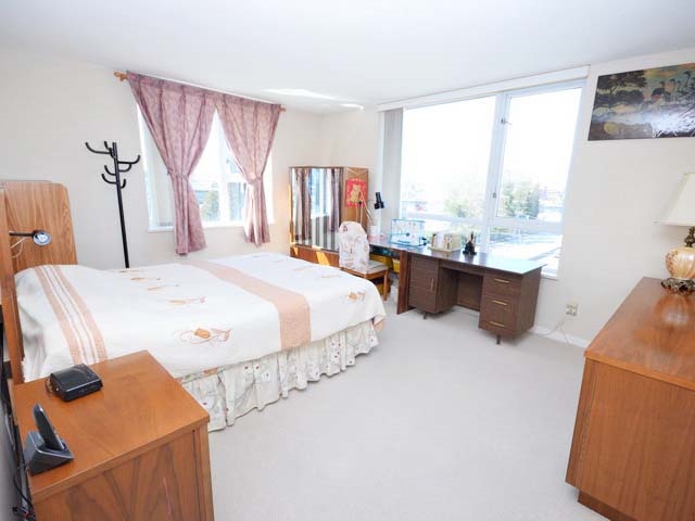 The primary bedroom on the corner, windows on two sides and a desk under the far one.