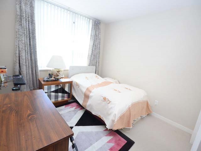 A third bedroom, curtained window, a bed and a desk along the far wall.