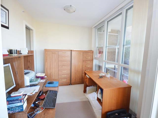 The fourth bedroom in use as a study, a desk under the windows and cabinets along the wall.