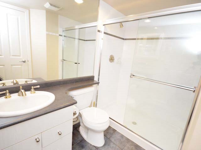 The second bathroom, vanity and mirror with the shower behind glass.